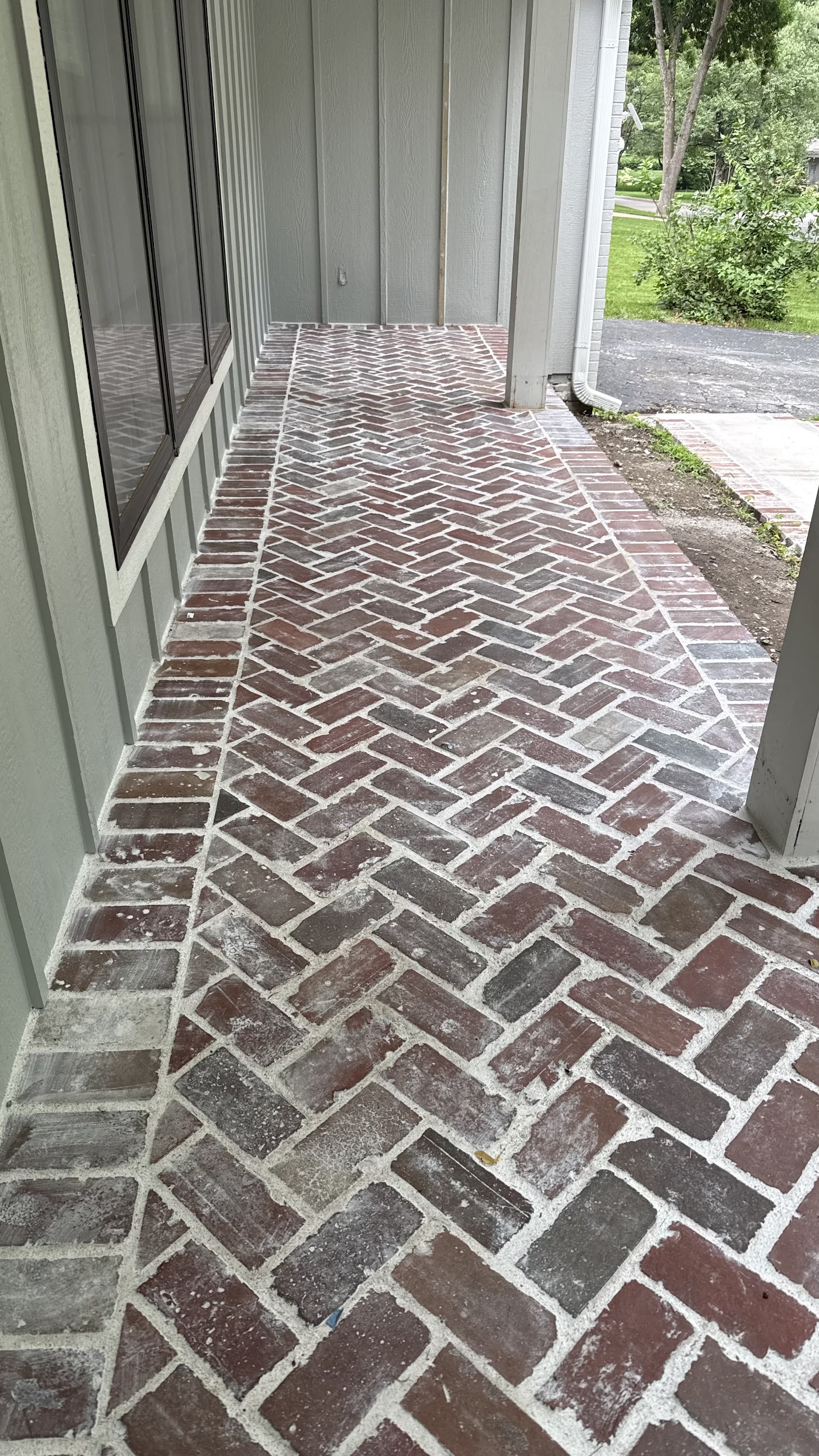 A herringbone brick walkway laid along a home, set by Meyer Masonry